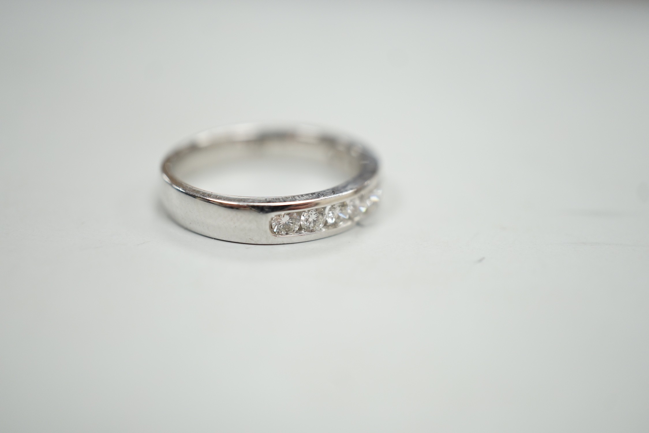 A modern 18k white metal and ten stone channel set diamond half eternity ring, size L/M, gross weight 4.1 grams.